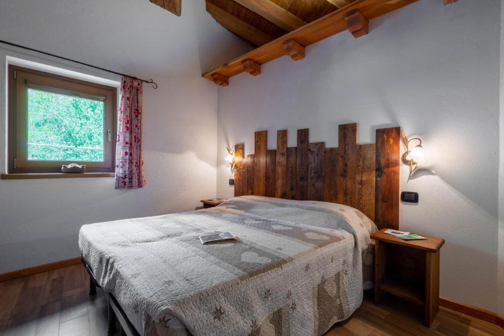 sypialnia z łóżkiem z drewnianym zagłówkiem i oknem w obiekcie Le Vieux Noyer - Appartamenti al Verde villaggio di Rumiod w mieście Saint-Pierre