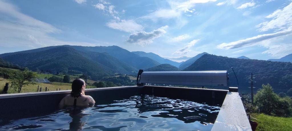 a woman sitting in a swimming pool with a view of mountains at Maison d'Hôtes Le shorten in Hèches
