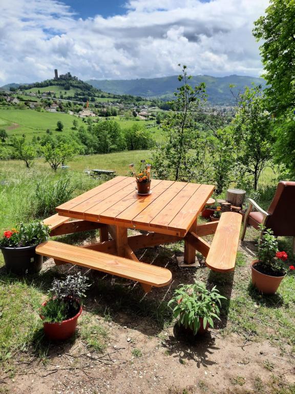 un tavolo da picnic in legno e panche in un campo di Les coteaux de Planèze, chambre pour 2, 3 ou famille nombreuse 2 adultes 5 enfants et jeunes a Belmont-Bretenoux