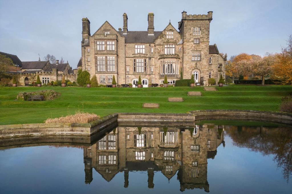 um velho castelo com um reflexo na água em Delta Hotels by Marriott Breadsall Priory Country Club em Derby