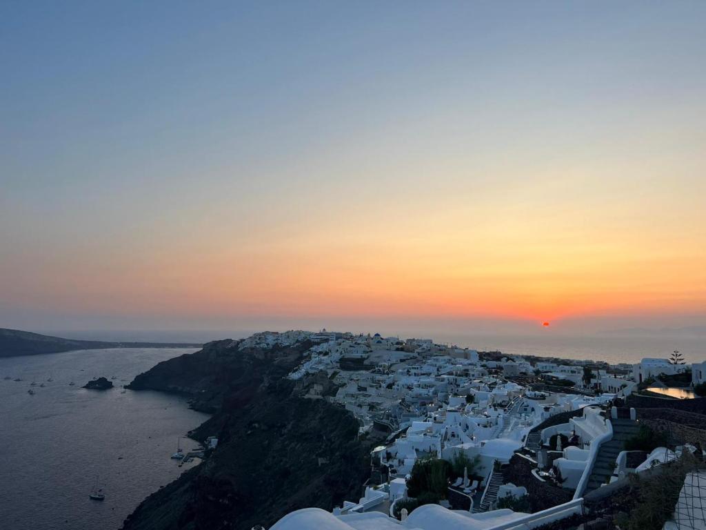 a view of a city with the ocean and the sunset at Captain John Villas Oia - Caldera & Sunset View in Oia