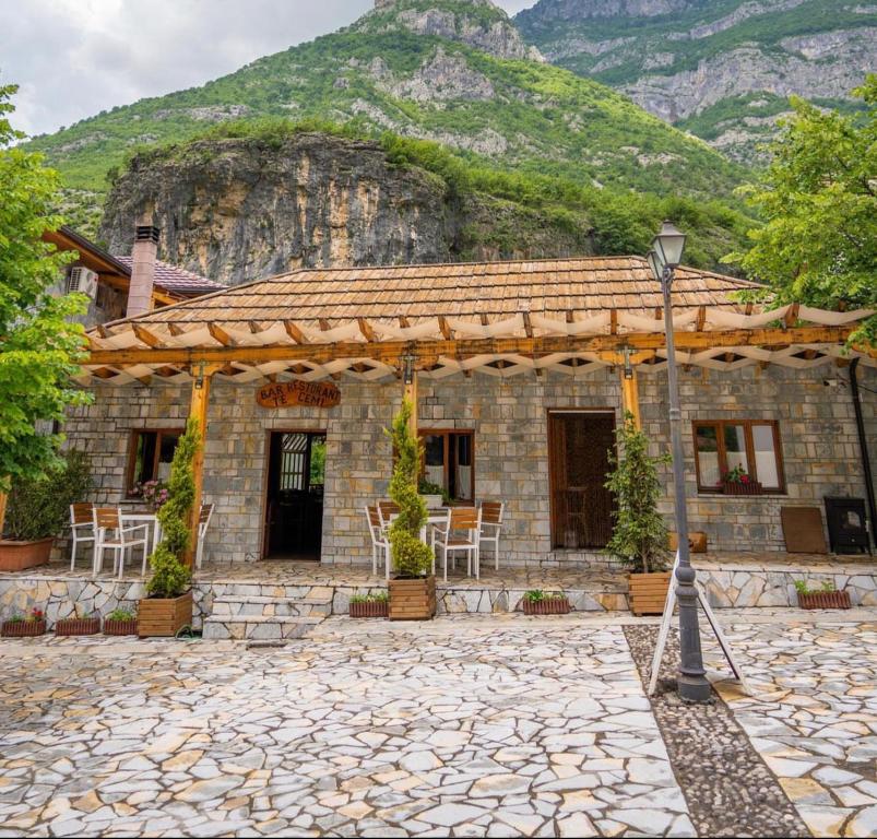 una casa de piedra frente a una montaña en Te Cemi - Restorant - Hotel, en Tamarë