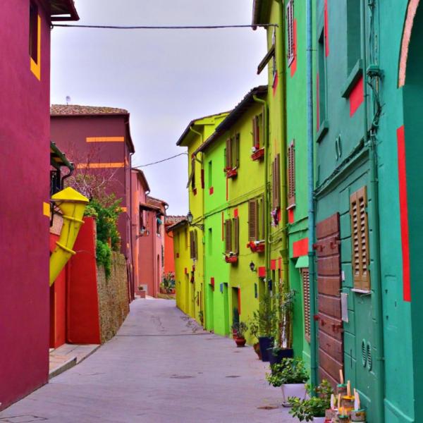 een smal steegje met kleurrijke gebouwen in een stad bij Saba's House in Ghizzano