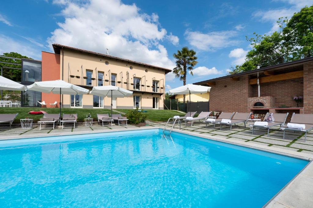 a swimming pool with chairs and umbrellas next to a building at Casa San Grato in Monteu Roero