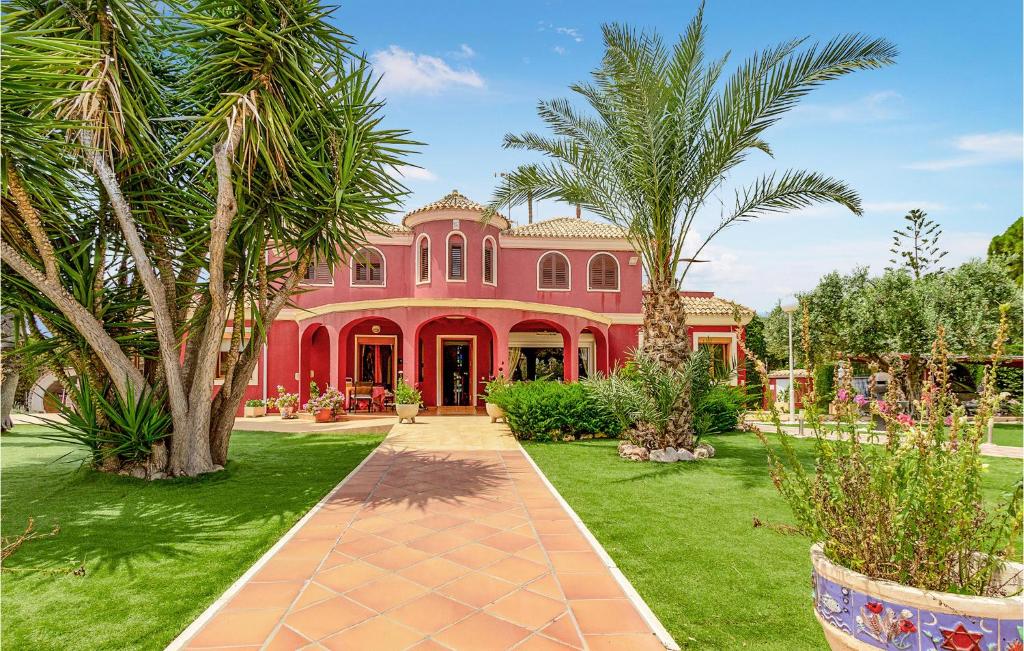 a red house with palm trees in front of it at Lovely Home In Elche With Kitchenette in Elche