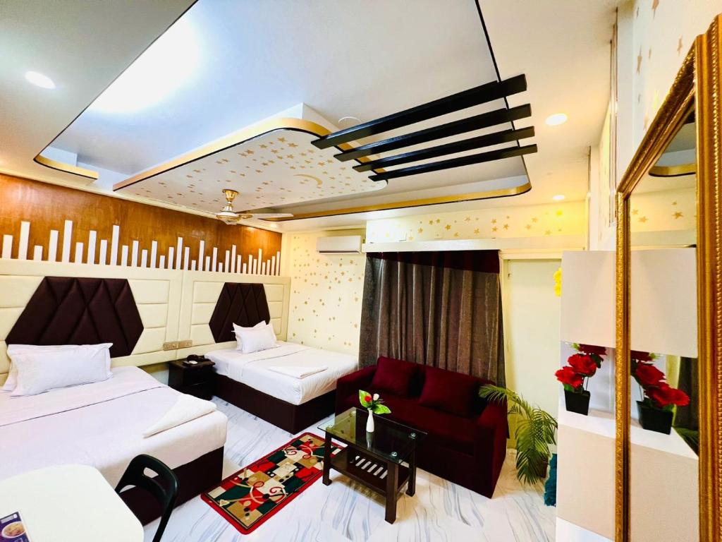 a hotel room with two beds and a red couch at HOTEL BLUE BIRD in Dhaka