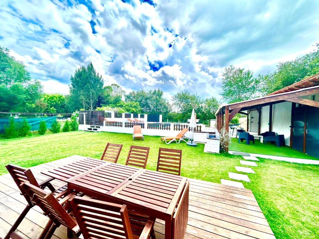 een patio met een houten tafel en stoelen in een tuin bij Superbe Villa Piscine Chauffée classée 4 étoiles in Aureilhan