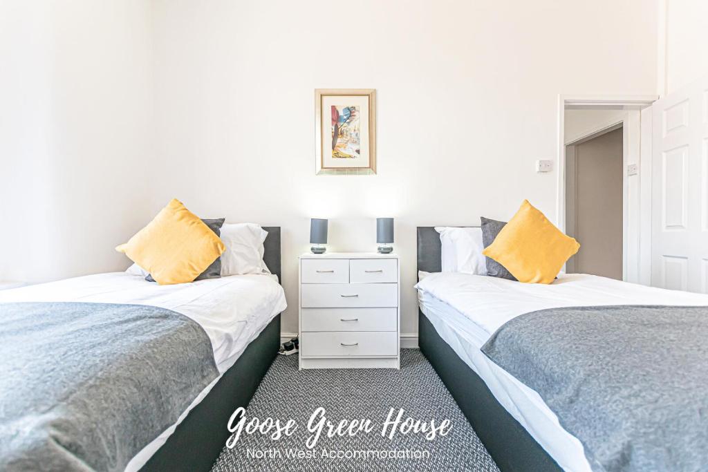 two beds in a bedroom with yellow pillows at Goose Green Contractor Accommodation in Pemberton