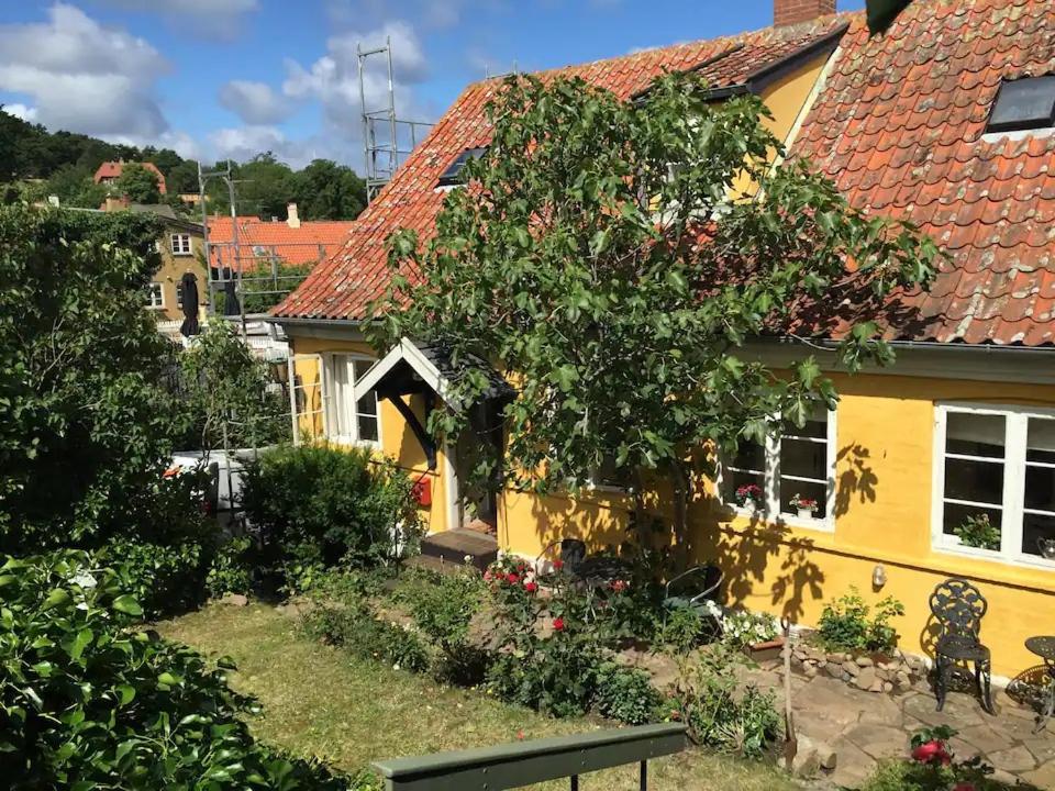 a yellow house with a tree in front of it at CHARMING FARM HOUSE IN GUDHJEM in Gudhjem