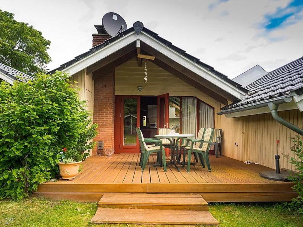 ein Haus mit einer Holzterrasse mit einem Tisch und Stühlen in der Unterkunft Ferienhaus "Sören" in Glücksburg
