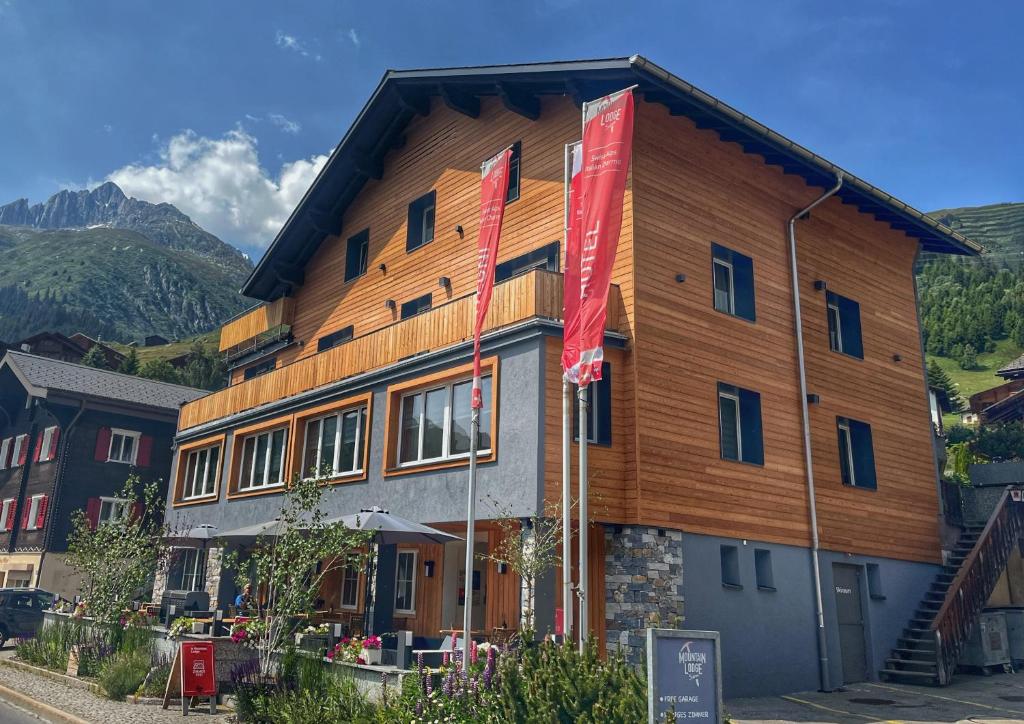 a large wooden building with flags in front of it at Mountain Lodge Sedrun in Sedrun