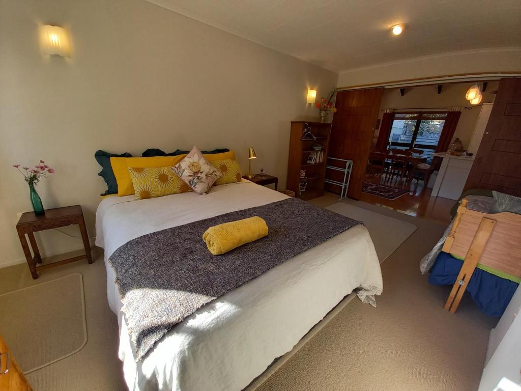 a bedroom with a large bed with a yellow pillow on it at Birds Eyes Te Awanga in Te Awanga