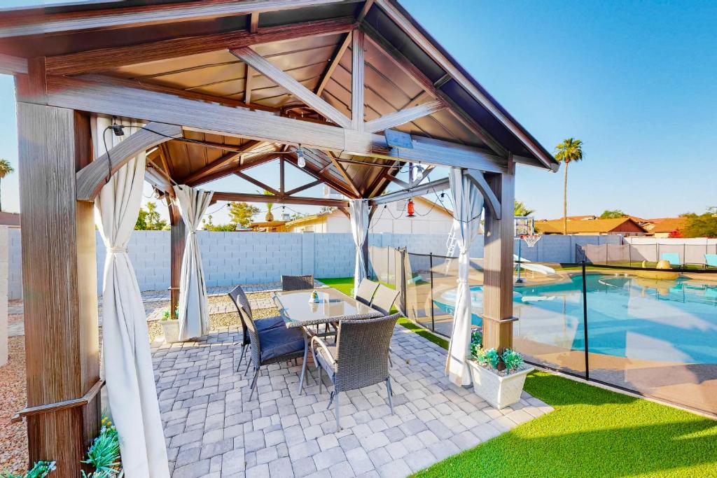 a pavilion with a table and chairs next to a pool at Pleasant Daydreams in Chandler