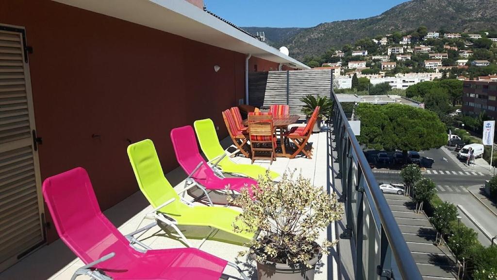 un patio con mesas y sillas de colores en un balcón en T3 Le Lavandou ideally placed 80m² of terraces, en Le Lavandou