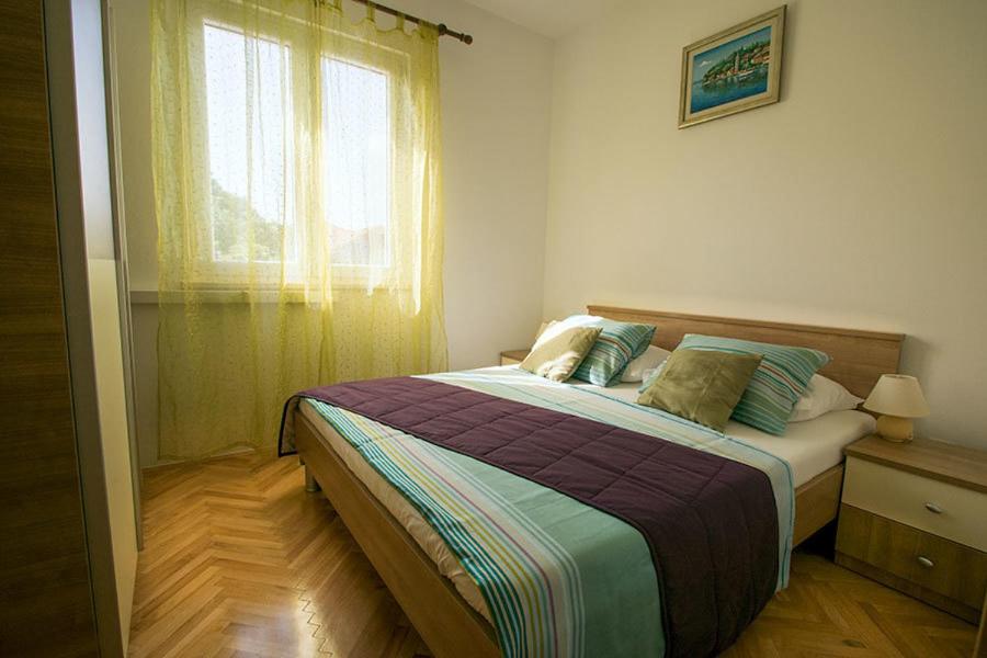 a bedroom with a large bed with a window at Apartments Miljanic in Cavtat