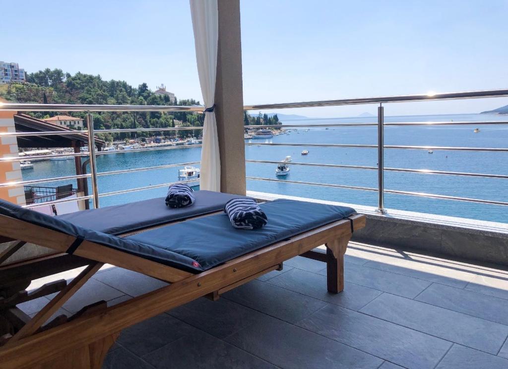 a bed on a balcony with a view of the water at Seafront 2-bedroom apartment Nika - Rabac in Rabac