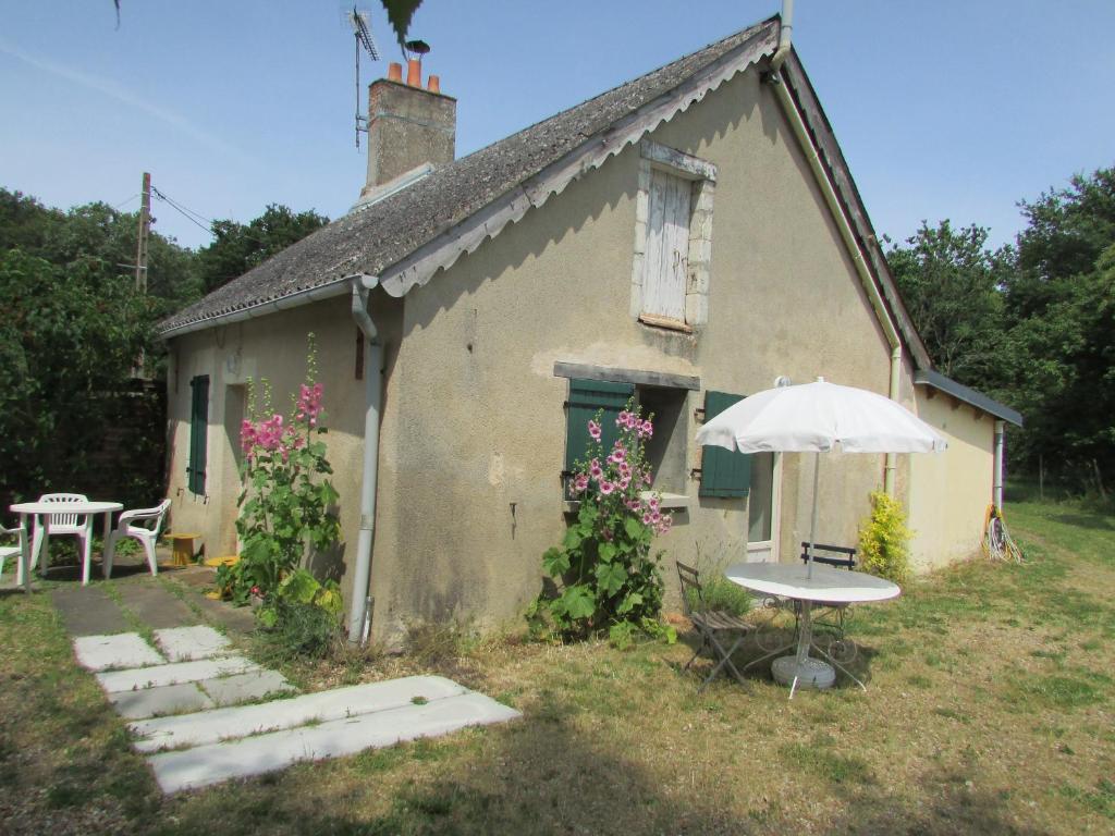 a small house with a table and an umbrella at Gite la petite pataudiere in Le Guédéniau