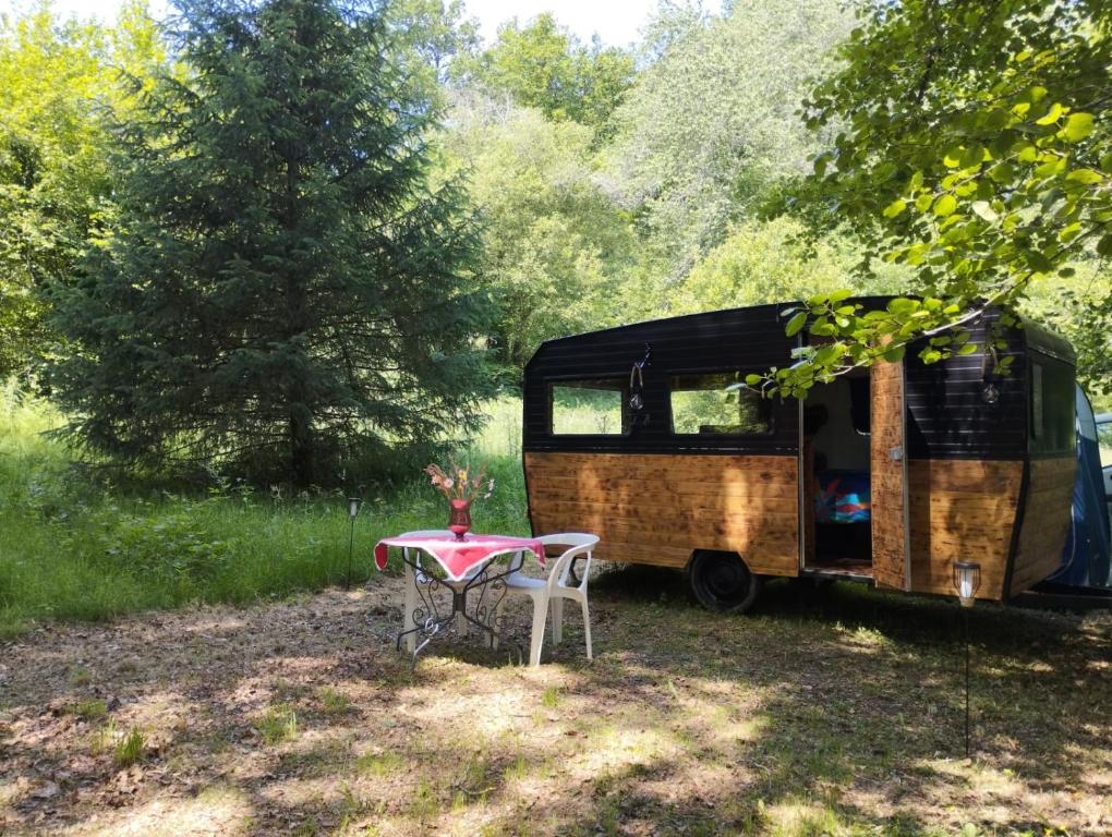 una caravana estacionada en un campo con una mesa en La caravane nature, en Saint-Julien-le-Petit