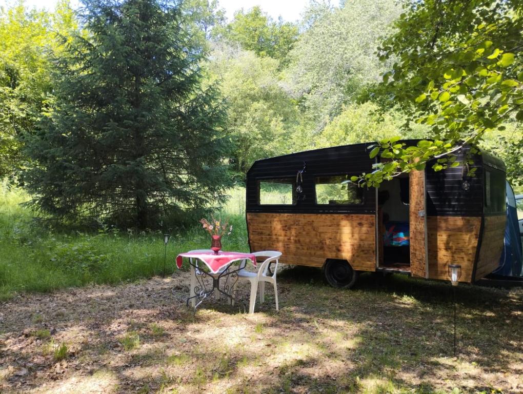 un camping-car garé dans un champ avec une table dans l'établissement La caravane nature, à Saint-Julien-le-Petit
