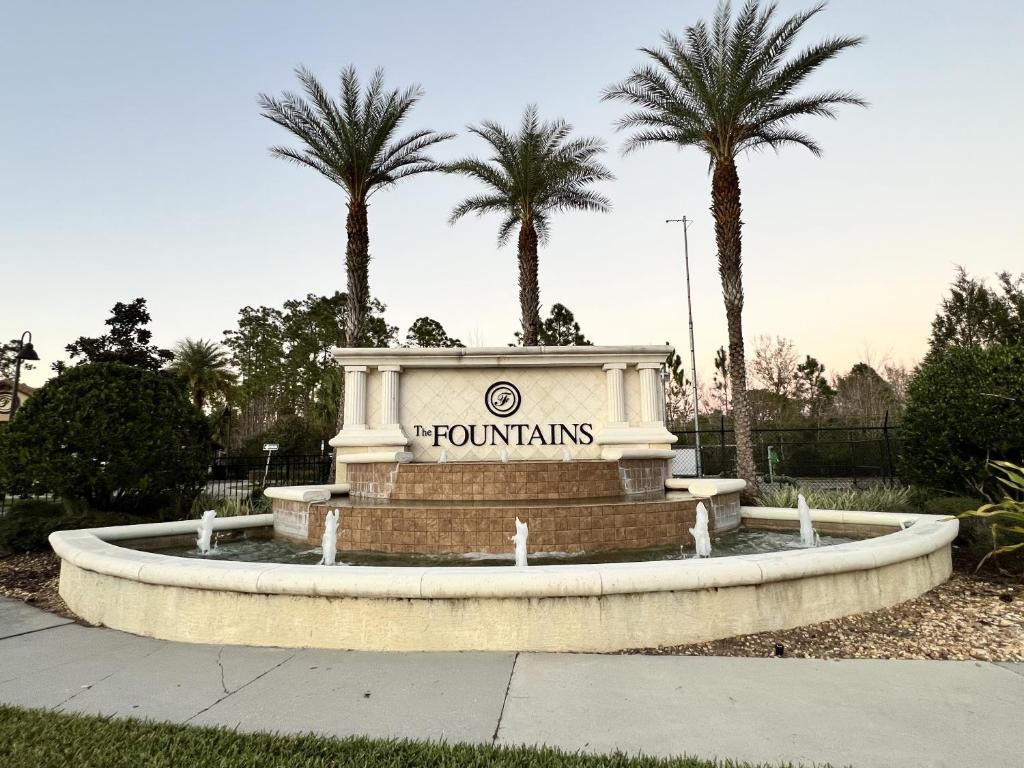 a fountain in a park with palm trees in the background at 8225RB-The Fountains at ChampionsGate townhouse in Kissimmee