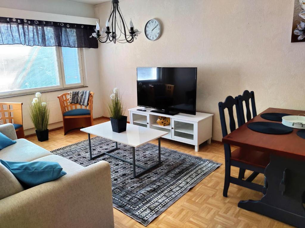 uma sala de estar com uma televisão de ecrã plano e uma mesa em Yyterin portti em Pori