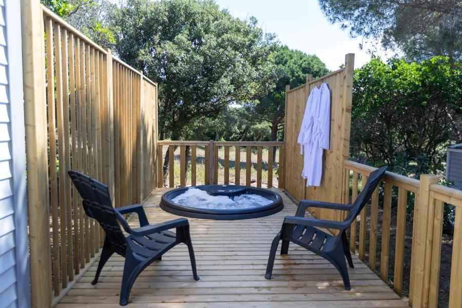 2 chaises et une table sur une terrasse en bois dans l'établissement Camping Le Damier, à Pianottoli-Caldarello