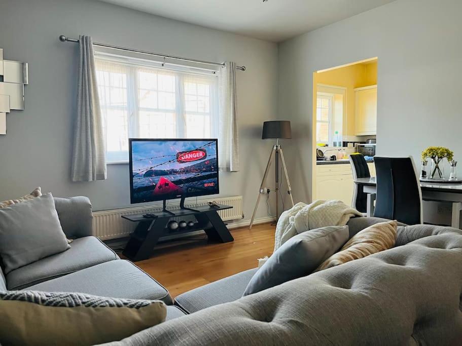 uma sala de estar com um sofá e uma televisão de ecrã plano em Cozy Luxurious Apartment em Edgware