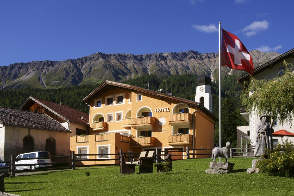 ein großes Gebäude mit einer Flagge davor in der Unterkunft Hotel Landgasthof Staila in Fuldera