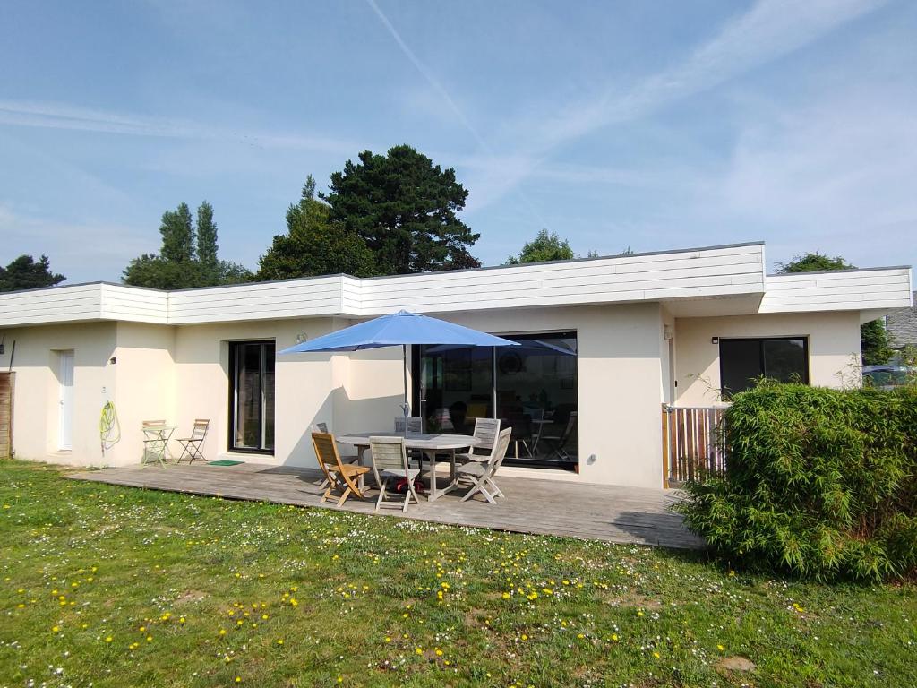 a house with a table and chairs and an umbrella at maison de vacances locquirec in Locquirec