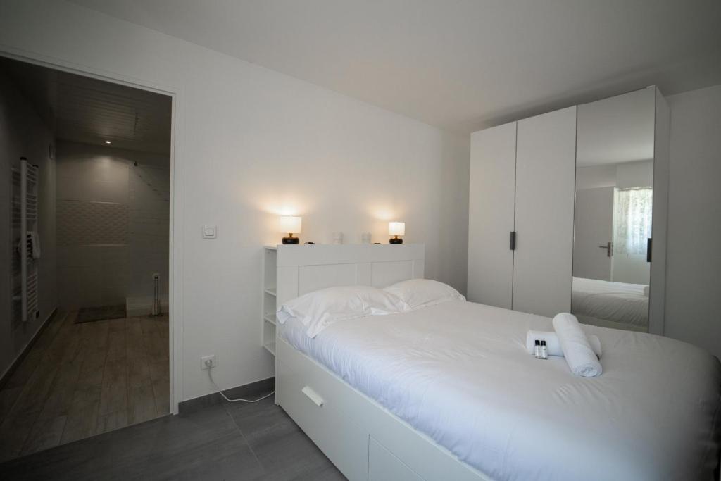 a white bedroom with a bed and a mirror at Les cerisiers un petit coin de paradis pour deux proche du lac! in Sévrier