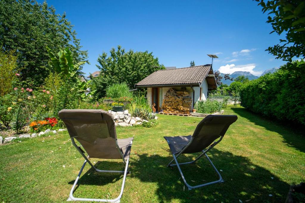 two chairs sitting in the grass in front of a house at Les cerisiers un petit coin de paradis pour deux proche du lac! in Sévrier