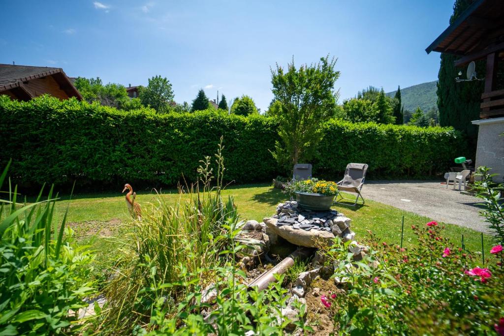 a garden with a chair and a pot of flowers at Les cerisiers un petit coin de paradis pour deux proche du lac! in Sévrier