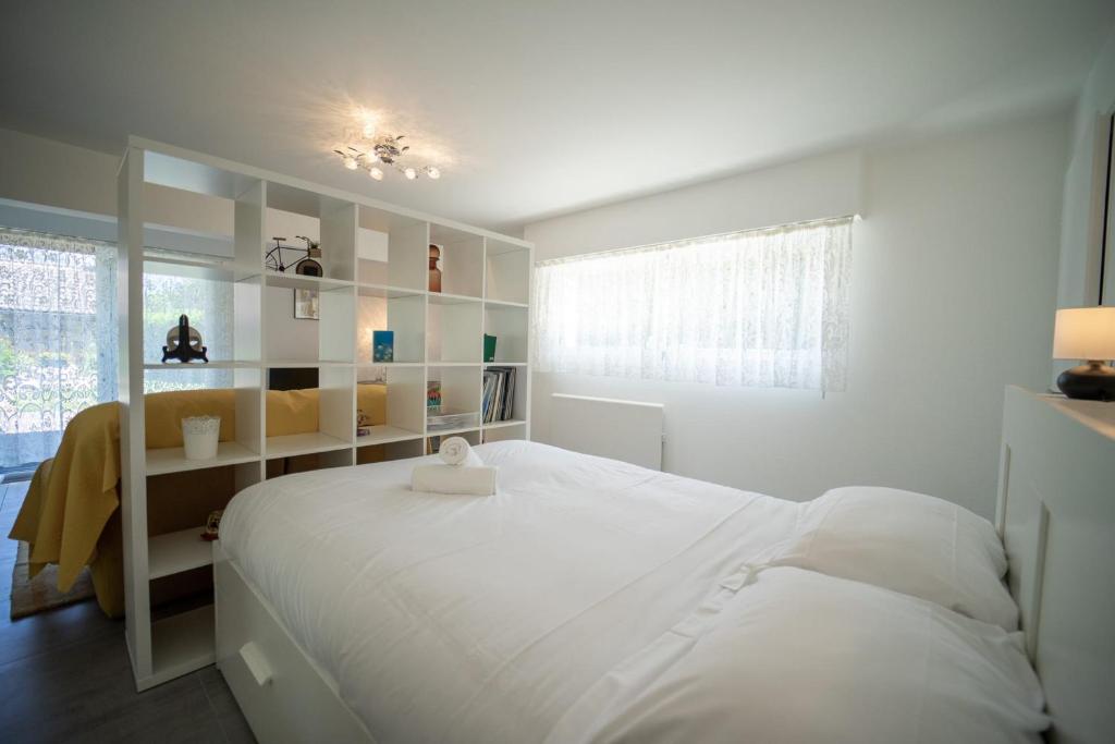 a white bedroom with a large bed and a window at Les cerisiers un petit coin de paradis pour deux proche du lac! in Sévrier