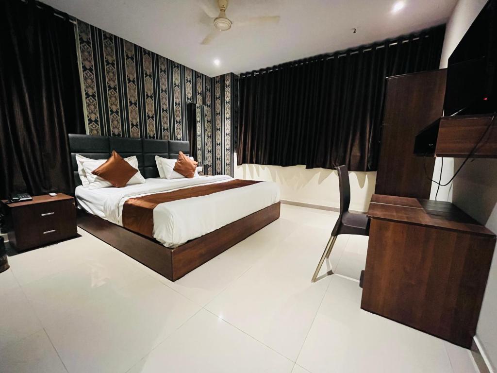 a bedroom with a bed and a desk and a bed sidx sidx sidx at Hotel Nova Vesu in Surat