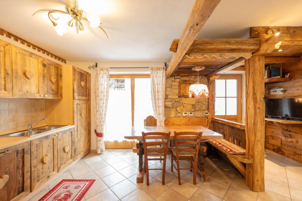 een keuken met houten kasten en een tafel en stoelen bij Cesa Anna in Campitello di Fassa