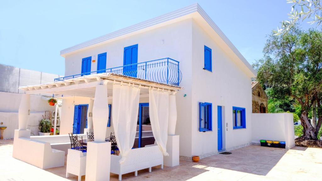 ein weißes Haus mit blauen Fenstern und einem Balkon in der Unterkunft Villa dei Due Ulivi in Capo dʼOrlando