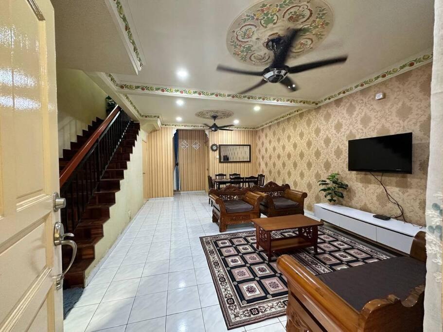 uma sala de estar com uma ventoinha de tecto e uma televisão em Homestay Jati by NazTi em Seremban