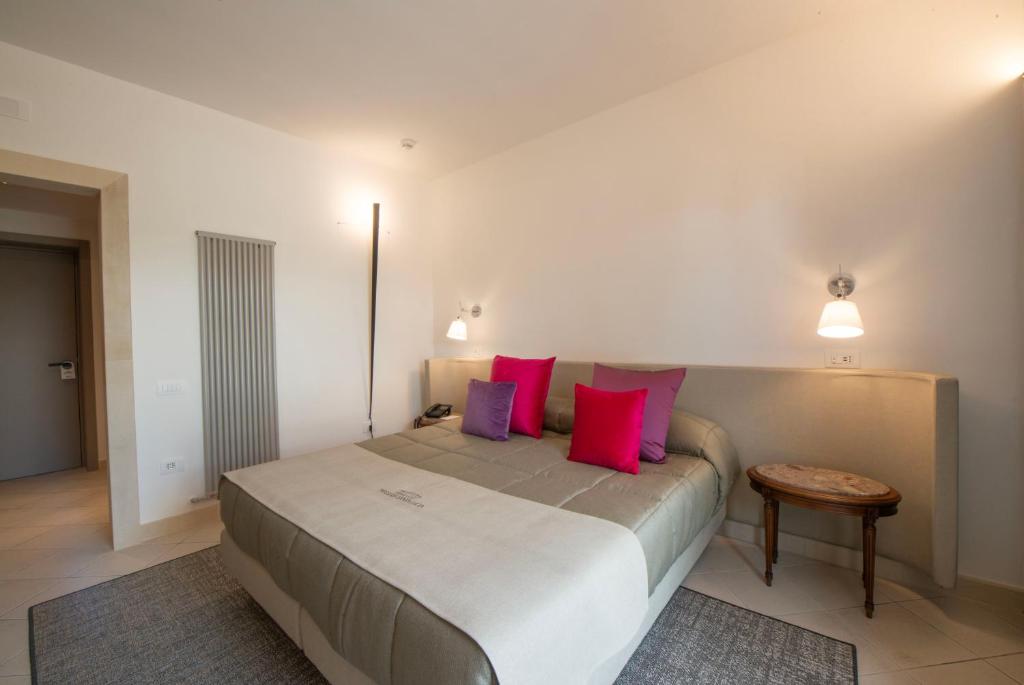 a bedroom with a large bed with red and purple pillows at Grand Hotel Masseria Santa Lucia in Ostuni