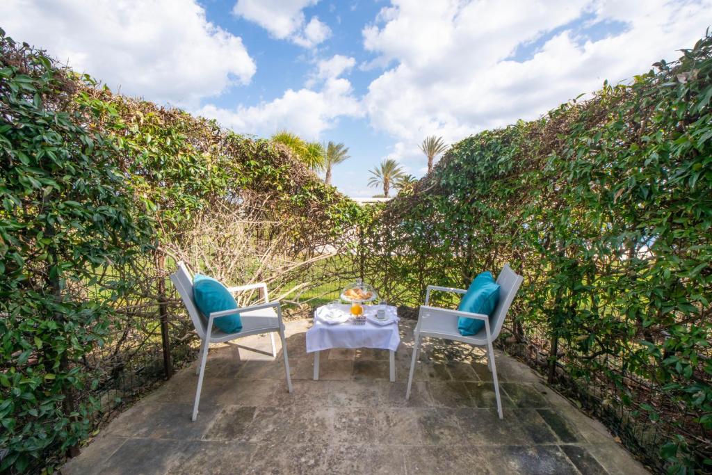 a table and two chairs sitting in front of a hedge at Grand Hotel Masseria Santa Lucia in Ostuni