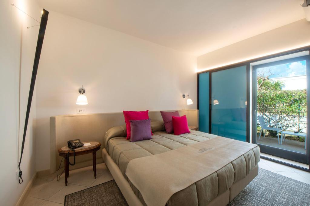 a bedroom with a large bed with pink pillows at Grand Hotel Masseria Santa Lucia in Ostuni