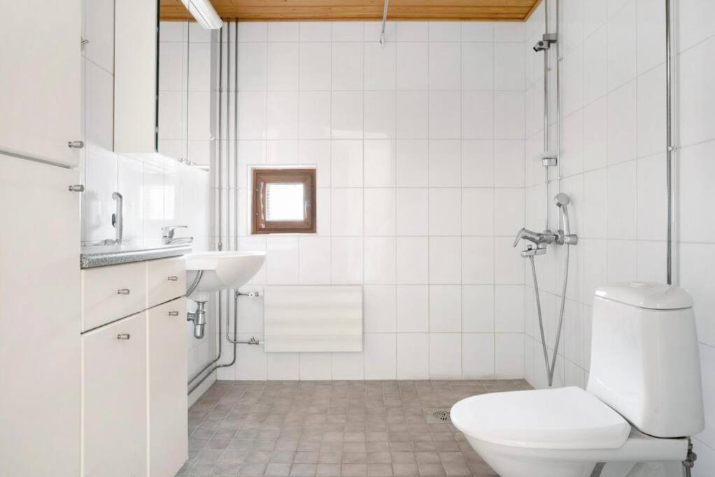 a white bathroom with a toilet and a sink at Studio by Sello shopping mall in Espoo