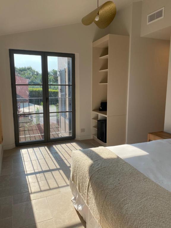 a bedroom with a bed and a large window at Lou Cagnard in Saint-Tropez