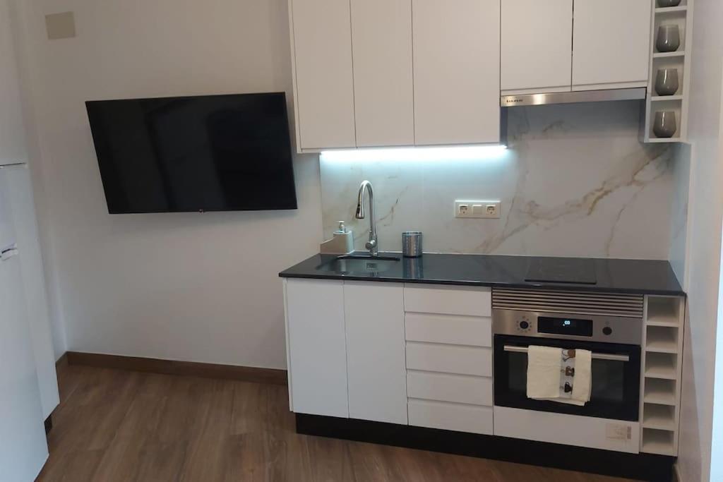 a kitchen with a stove and a sink and a tv at Apartamento Centroplaya in Bueu