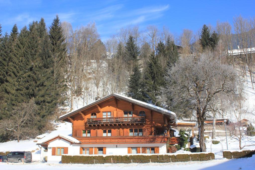 ein großes Holzhaus im Schnee mit Bäumen in der Unterkunft Uta's Ferienhof in Sankt Gallenkirch