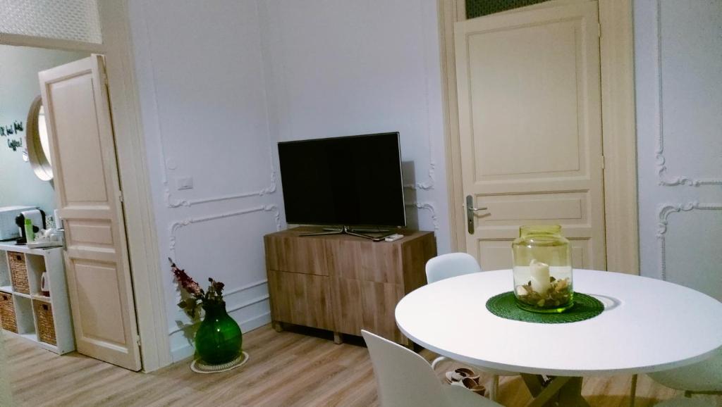 a white dining room with a white table and a tv at "La Madrice" Casa Vacanze in Bagheria