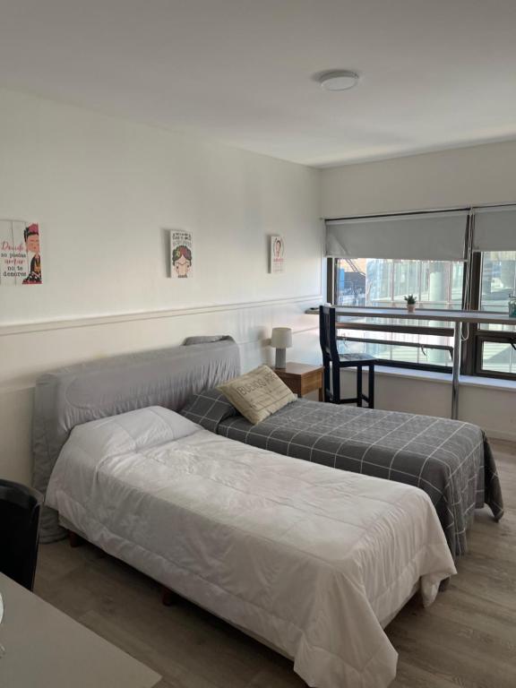 a bedroom with two beds and a desk and a window at Maipo 1501 in Buenos Aires