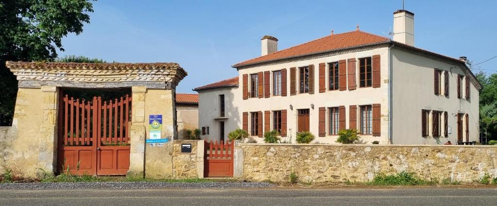 a white house with red doors and a stone wall at Chambre d'hôte Daugé in Saint-Cricq-Chalosse