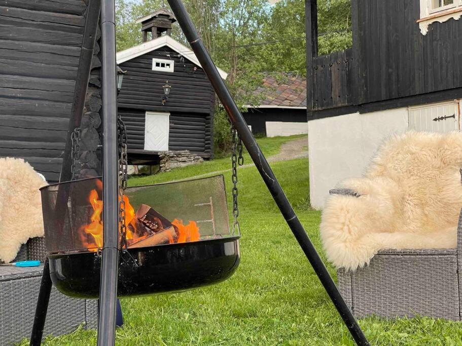 a fire grill in a yard with a dog laying next to it at Stabburet på Gaarder / wifi og sauna 