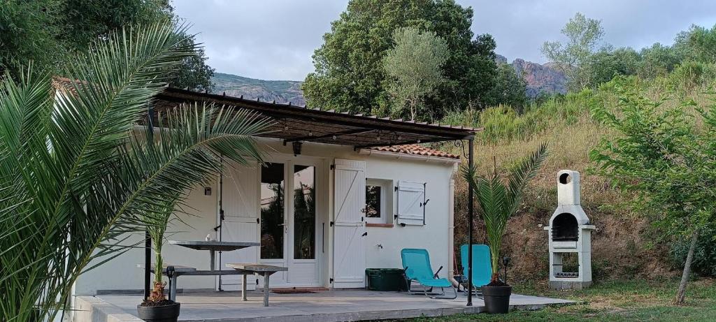une petite maison blanche avec deux chaises et une table dans l'établissement Charmante maisonnette situé au calme proche d'Ajaccio., à Afa