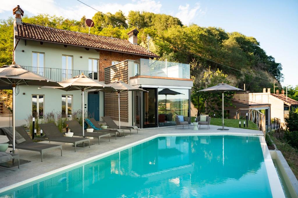 una casa con piscina con sillas y sombrillas en Relais Casa Clara, en Montaldo Roero